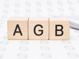 Drei hölzerne Würfel mit den Buchstaben A, G und B auf weißem Untergrund (KI-generiert)
