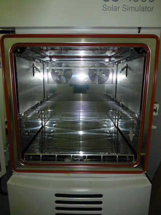 Laborgerät mit geöffneter Klapptür, innen beleuchtete Glasablagen und metallische Halterungen unter einer Beschriftung Solar Simulator (KI-generiert)